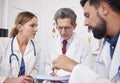 Three doctors discussing medical records in doctorÃ¢â¬â¢s office